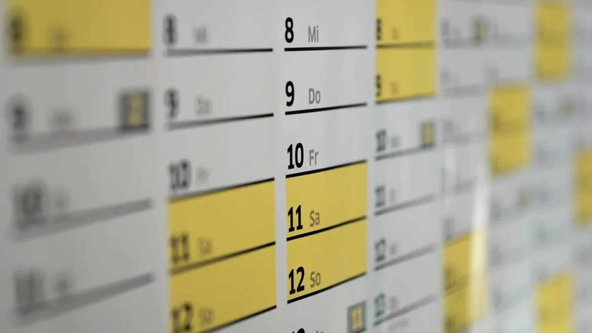 A wall calendar with booked days highlighted in yellow