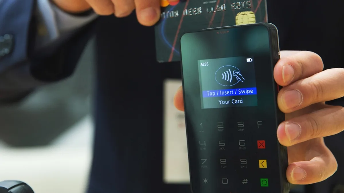A guest paying by card on a payment terminal at checkout