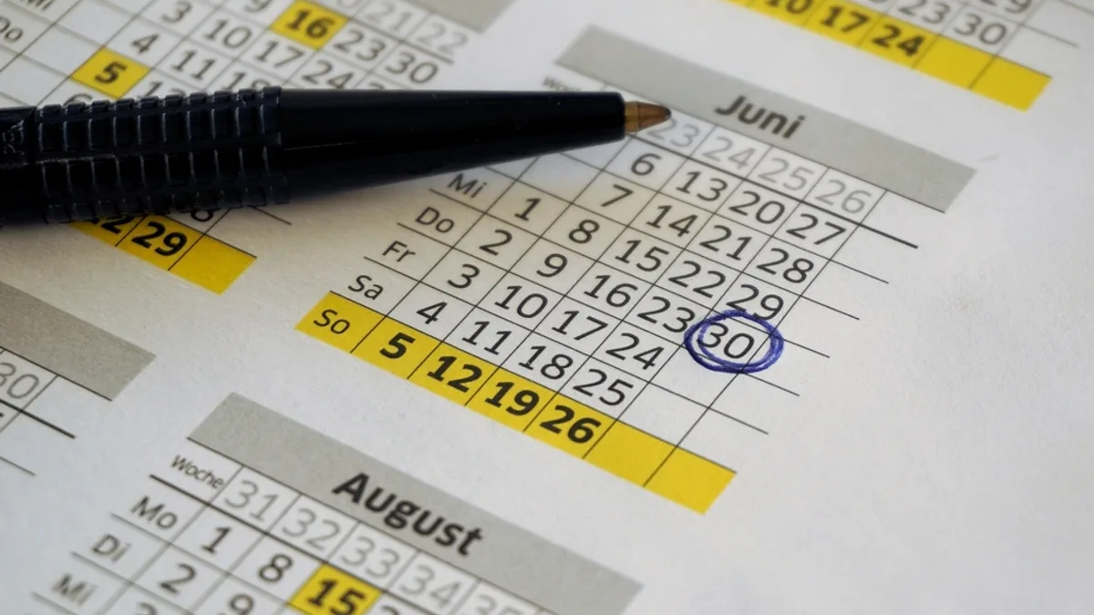 A printed calendar with a pen and a date circled in blue